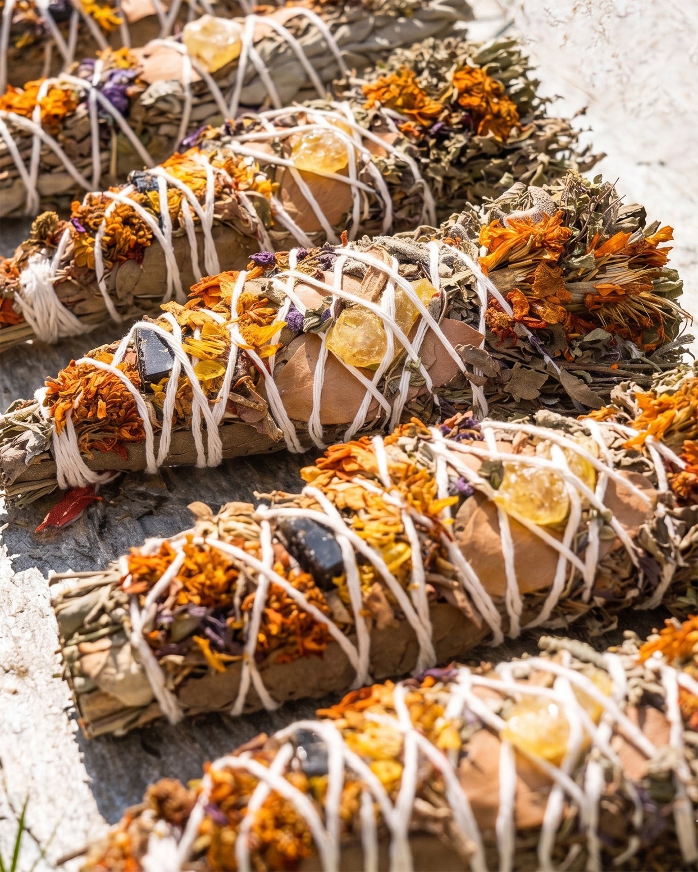 A row of artisanal Halimuyak ritual smudge sticks displaying a variety of dried Philippine herbs, flowers, and golden tree resins.