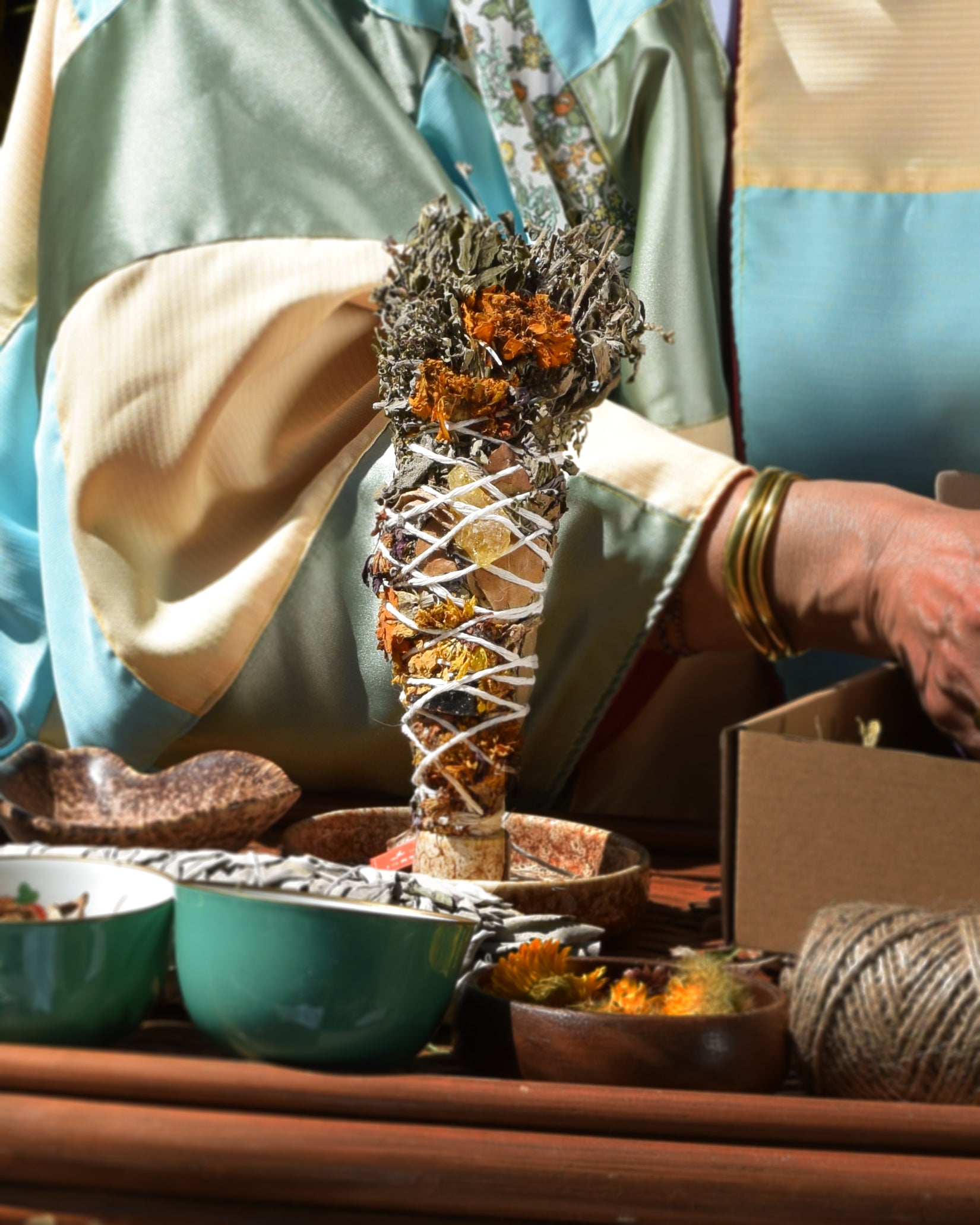 The Halimuyak ritual stick standing upright on a wooden tray, surrounded by ritual tools like ceramic bowls and twine.